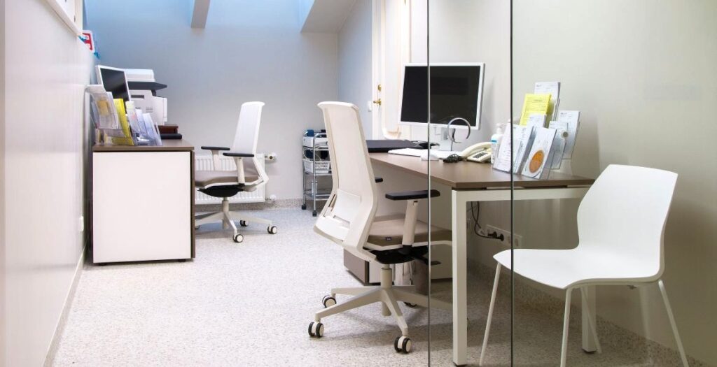 Modern consultation room with desks, chairs, and computer at Elite Clinic