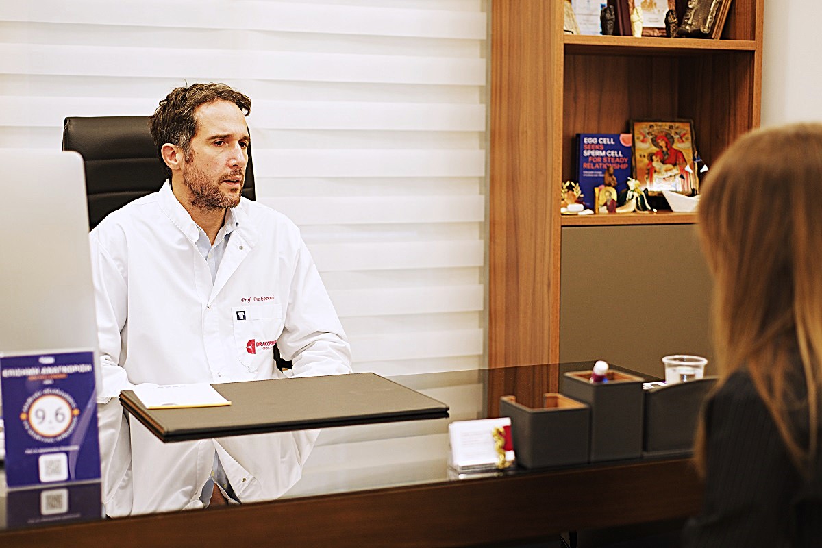 Fertility specialist in white coat consulting a female patient at Drakopoulos Reproductive Medicine IVF clinic in Athens, Greece – infertility treatment, gynecology, in vitro fertilization.